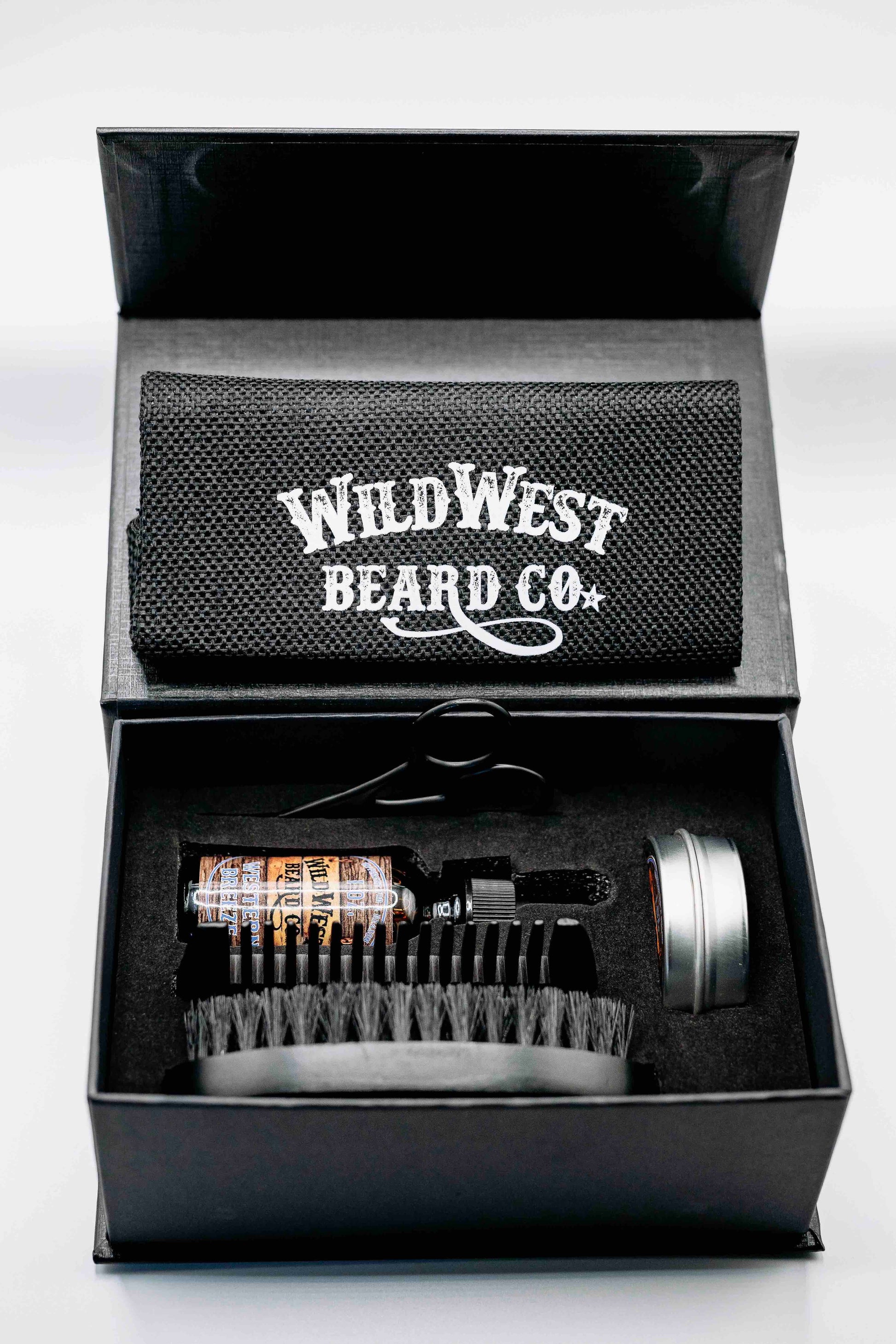 A clean picture of the Wild West Beard Co beard care gift box. With a travel bag, beard comb, beard brush, natural beard oil, natural beard balm, and snipping scissors.