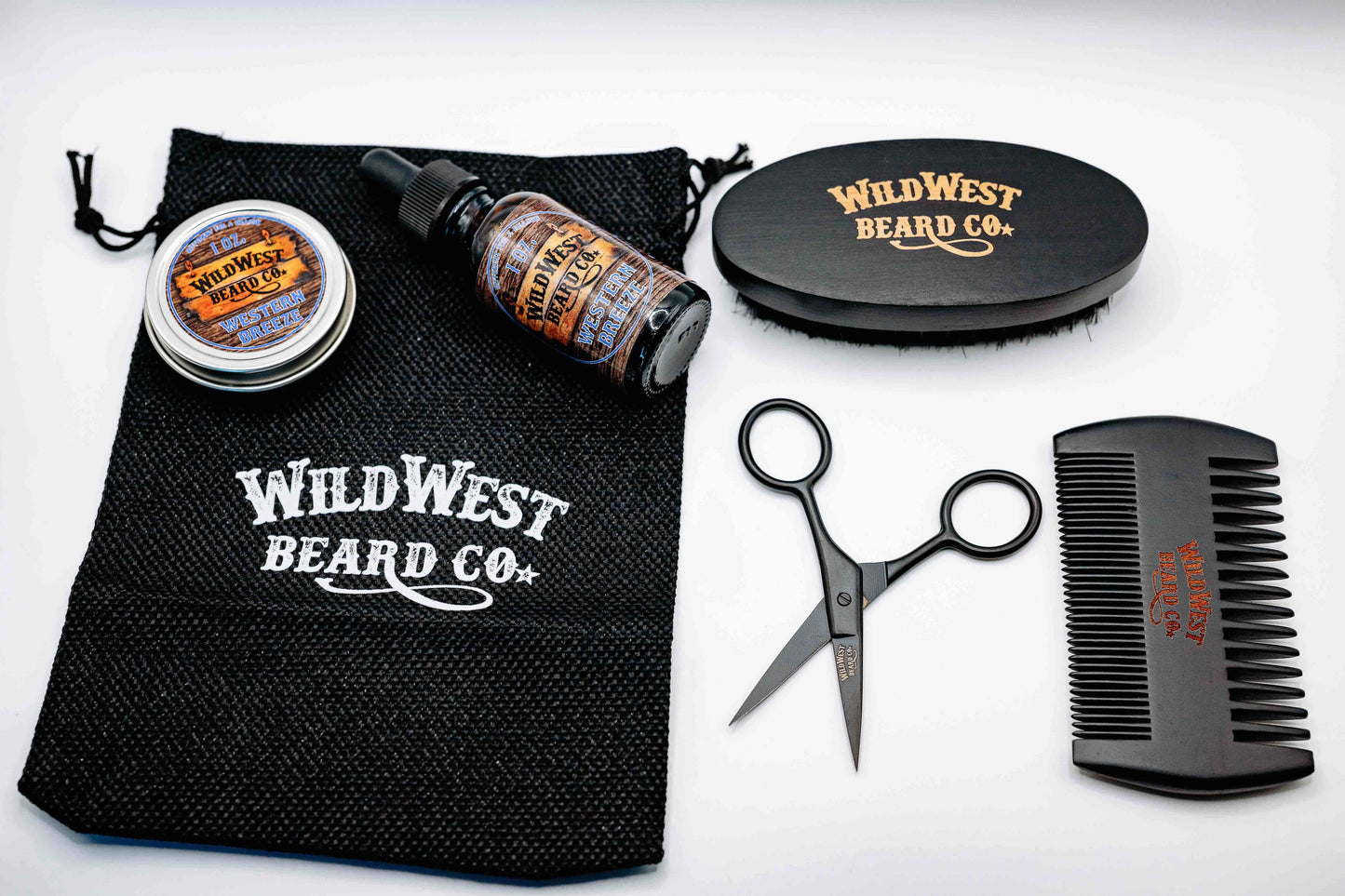 A clean picture of the Wild West Beard Co beard care starter kit contents. With a travel bag, beard comb, beard brush, natural beard oil, natural beard balm, and snipping scissors.
