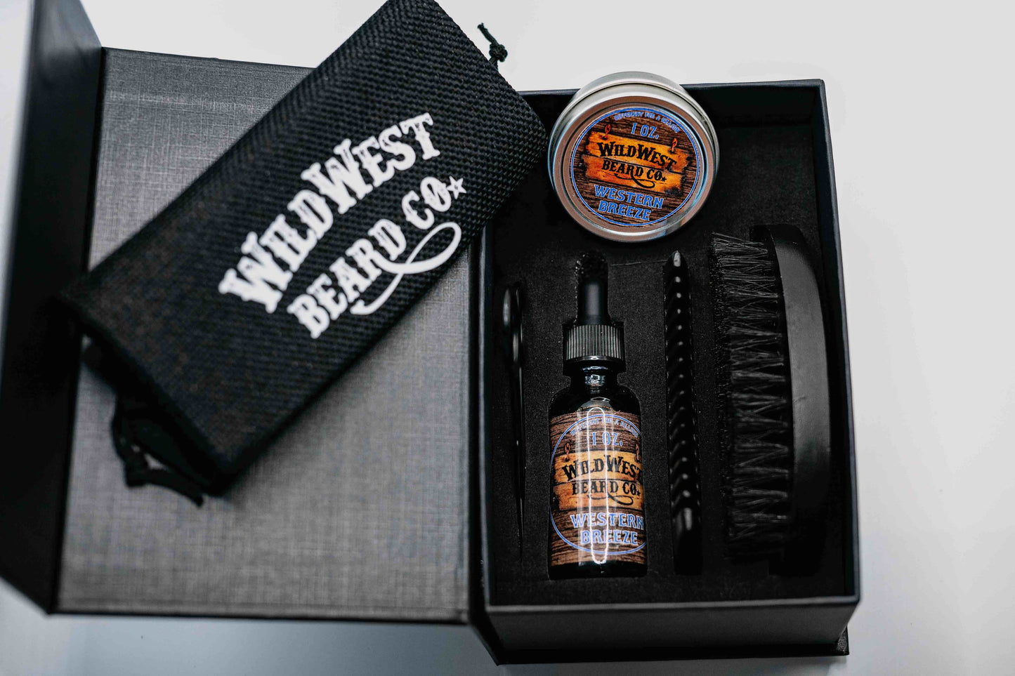 A clean picture of the Wild West Beard Co beard care gift box. With a travel bag, beard comb, beard brush, natural beard oil, natural beard balm, and snipping scissors.