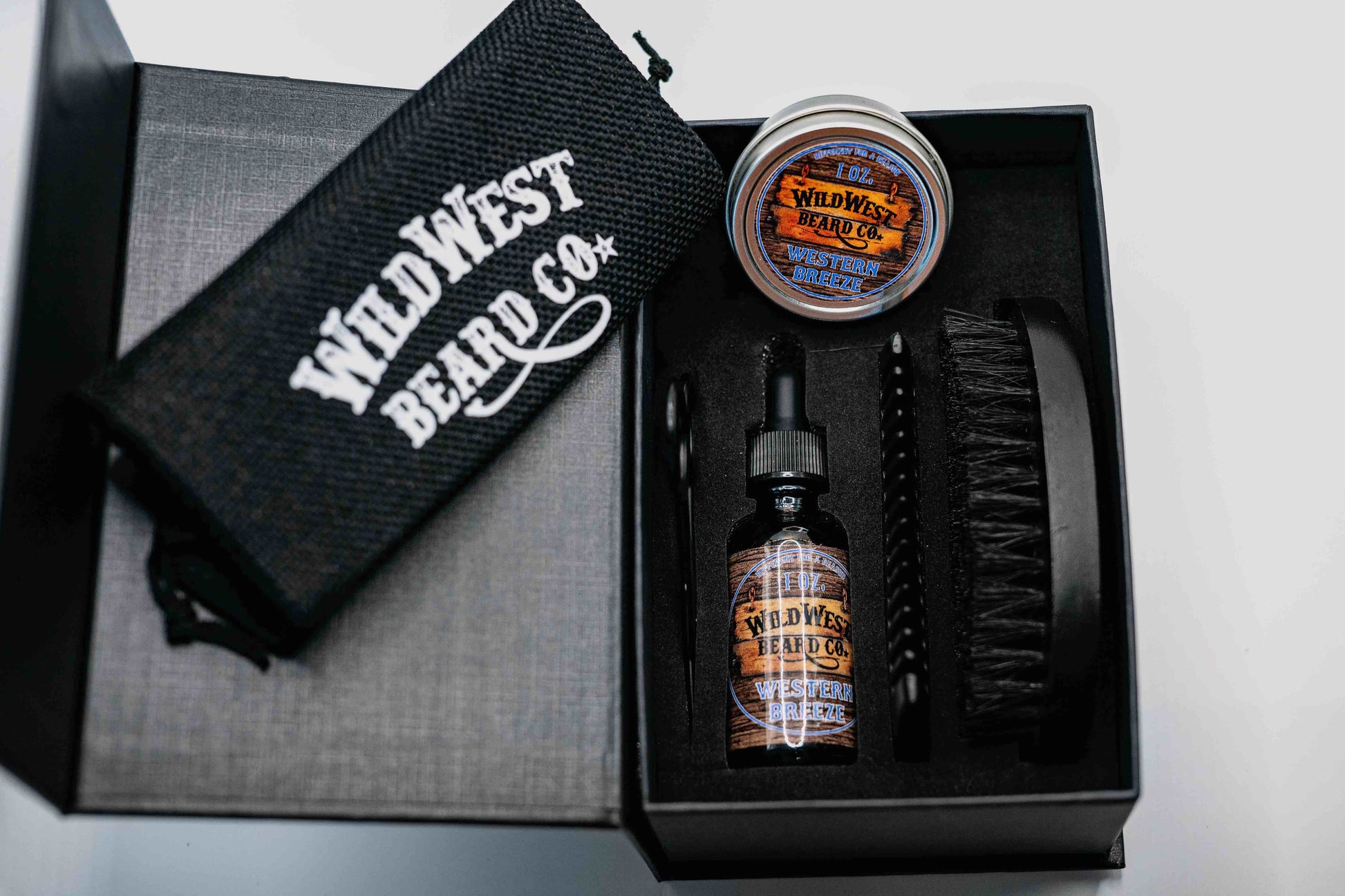 A clean picture of the Wild West Beard Co beard care gift box. With a travel bag, beard comb, beard brush, natural beard oil, natural beard balm, and snipping scissors.